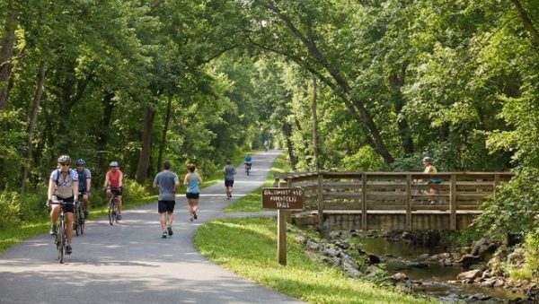 Cyclists and pedestrians on the Baltimore & Annapolis Trail over a wooden bridge