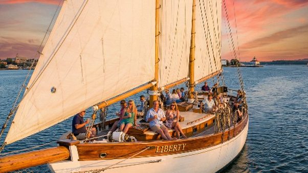 Schooner Liberty sails with passengers enjoying a sunset cruise, an old nearby attraction.