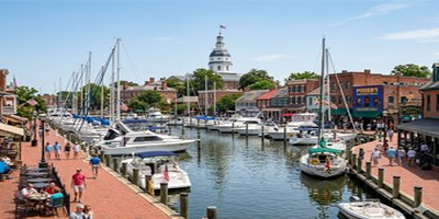 Boats docked at Annapolis Harbor Maryland with people strolling on the boardwalk