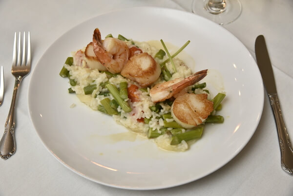 Seared scallops and shrimp with asparagus risotto, a fine dining dish.