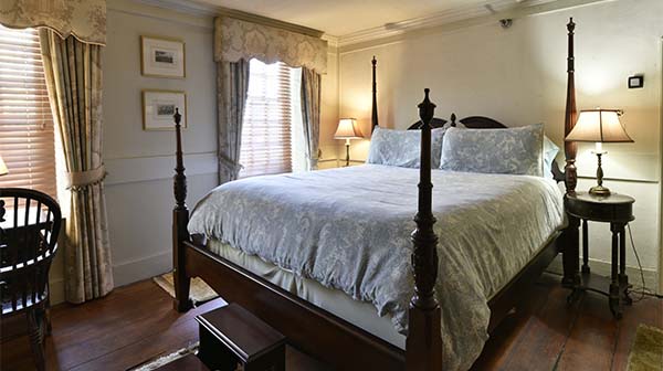 Bedroom with four-poster bed, bedside lamps, and wooden floor