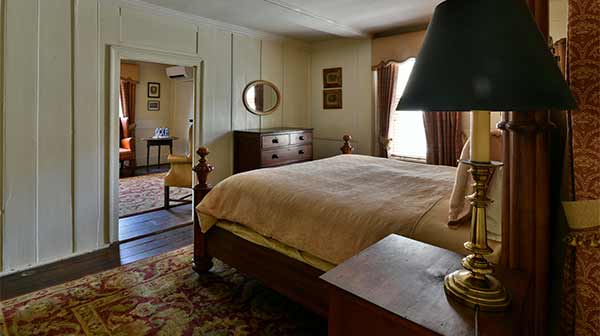 The Washington Suite: King bed, antique furniture, and a round mirror in a historic hotel room.