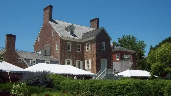 Historic brick house with white tents in foreground, possibly related to Jefferson suit.