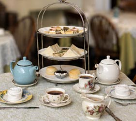 Elegant afternoon tea spread with teacups, sandwiches, and pastries