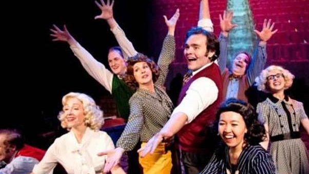 Ensemble of actors on stage in a musical theater production