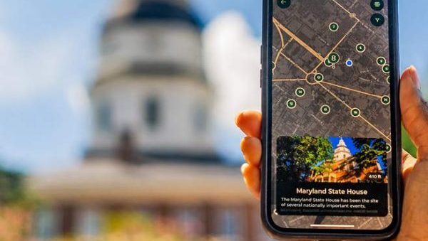 Person holding phone showing map of Maryland State House in front of Maryland State House