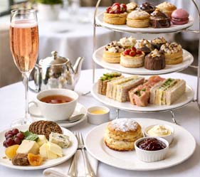 Elegant afternoon tea spread with sandwiches, scones, cakes, and champagne.