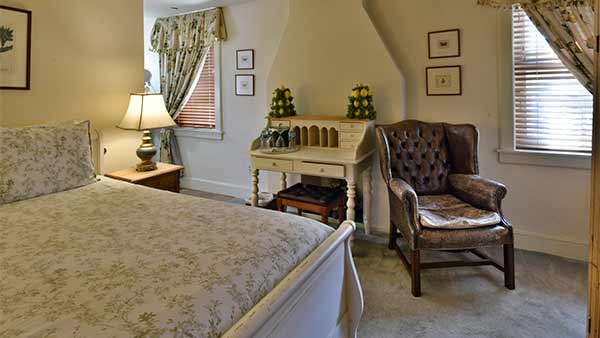 Mary Reynolds Room with bed, desk, chair, and vintage decor