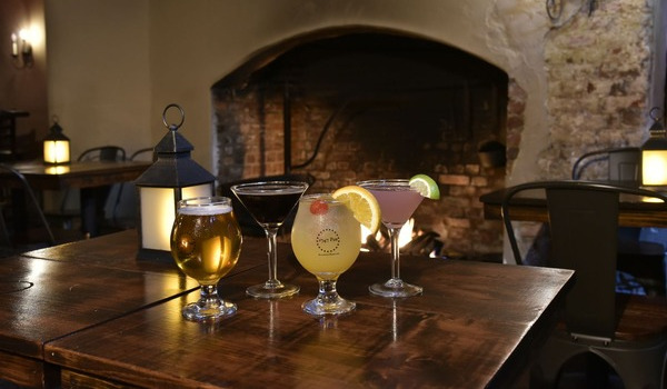 Cozy fine dining setting with cocktails and beer by a fireplace