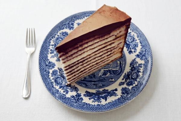 Slice of mille-feuille cake with chocolate ganache on a blue and white plate