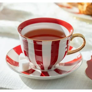 Red carousel stripes fine porcelain teacup and saucer with tea and sugar cubes.