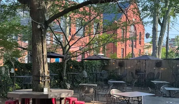 Outdoor seating area at The 1747 Pub with string lights and a church in background.