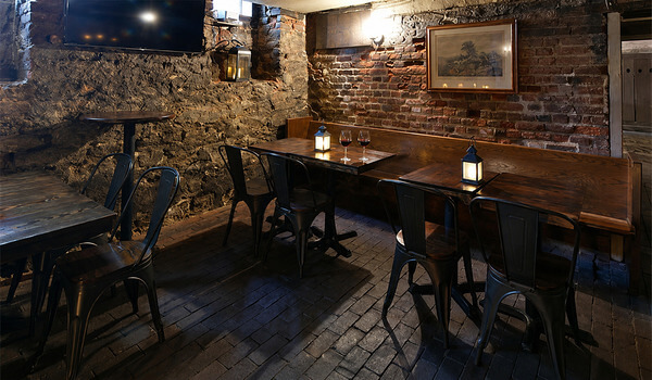Cozy pub interior with brick walls, wooden tables, and seating.